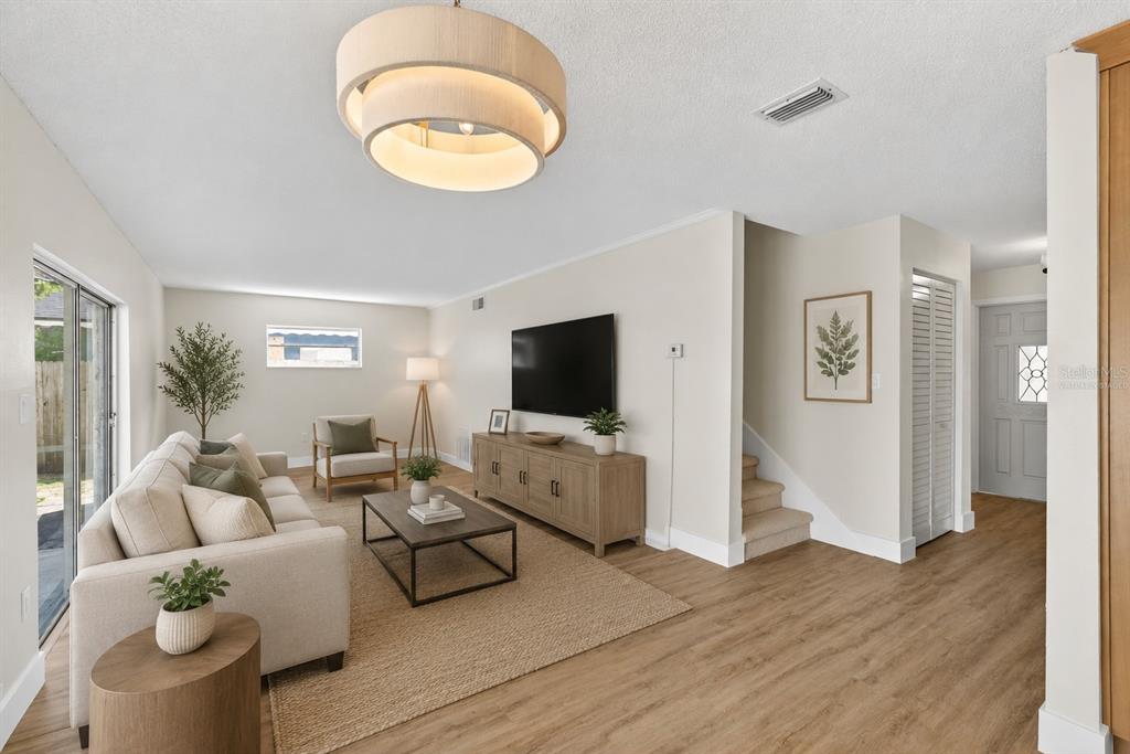 A living room features a beige sofa, a wood coffee table, and a wall-mounted television — 180 FLORIDA BOULEVARD, MERRITT ISLAND, FL