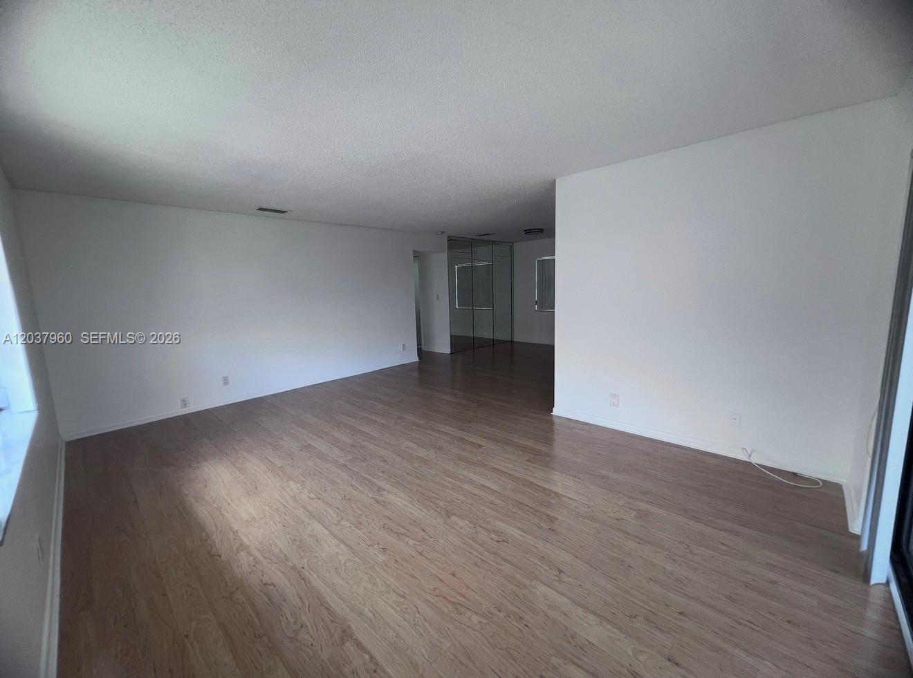 An empty room features light wood-look flooring, white walls, and a mirrored closet wall — 2430 SW 81st Ave # 408, Davie FL 33324, DAVIE, FL