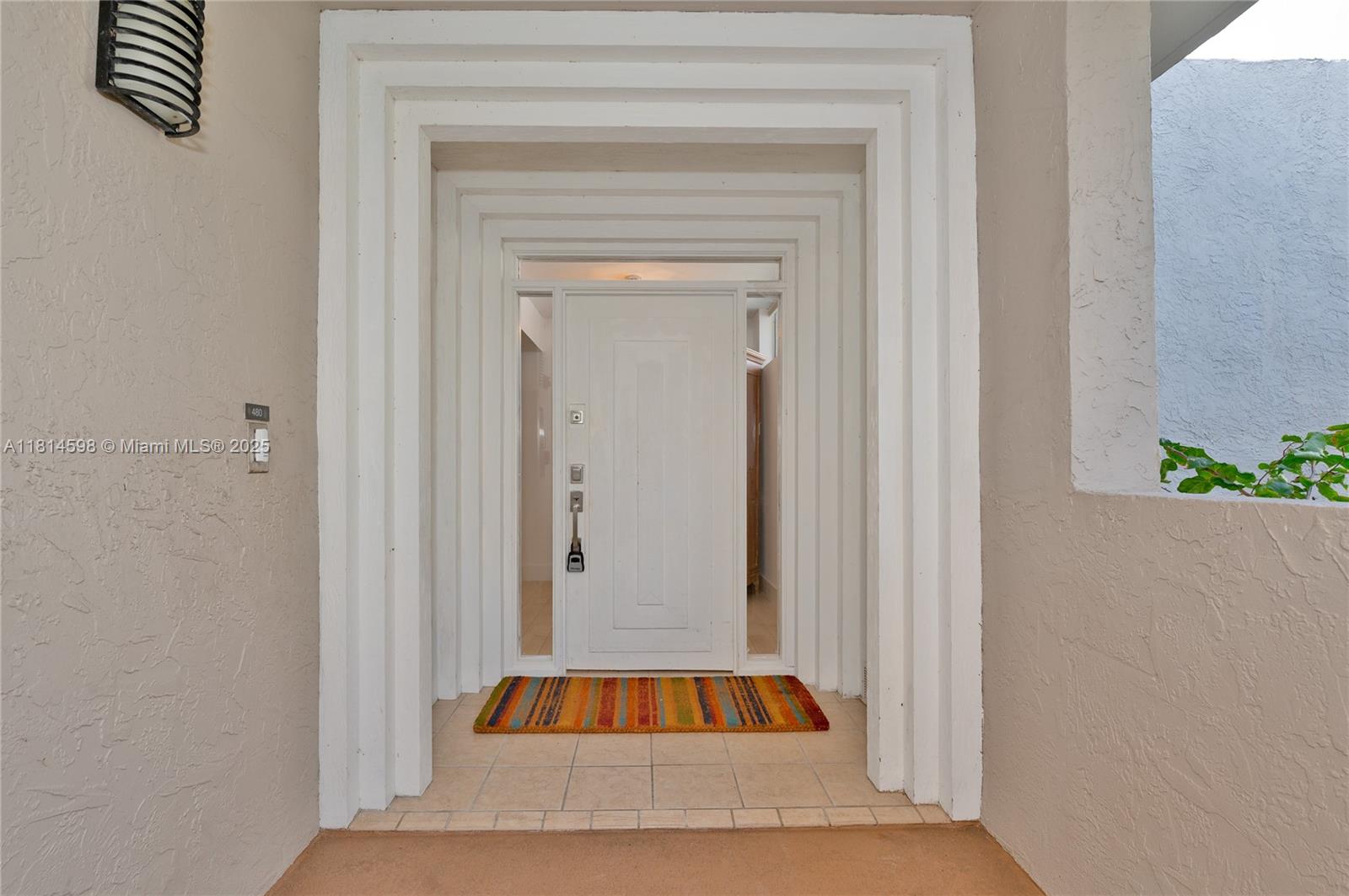 A white front door is framed by stepped molding and sits on a tiled entryway — 101 Crandon Blvd # 480, Key Biscayne FL 33149, KEY BISCAYNE, FL