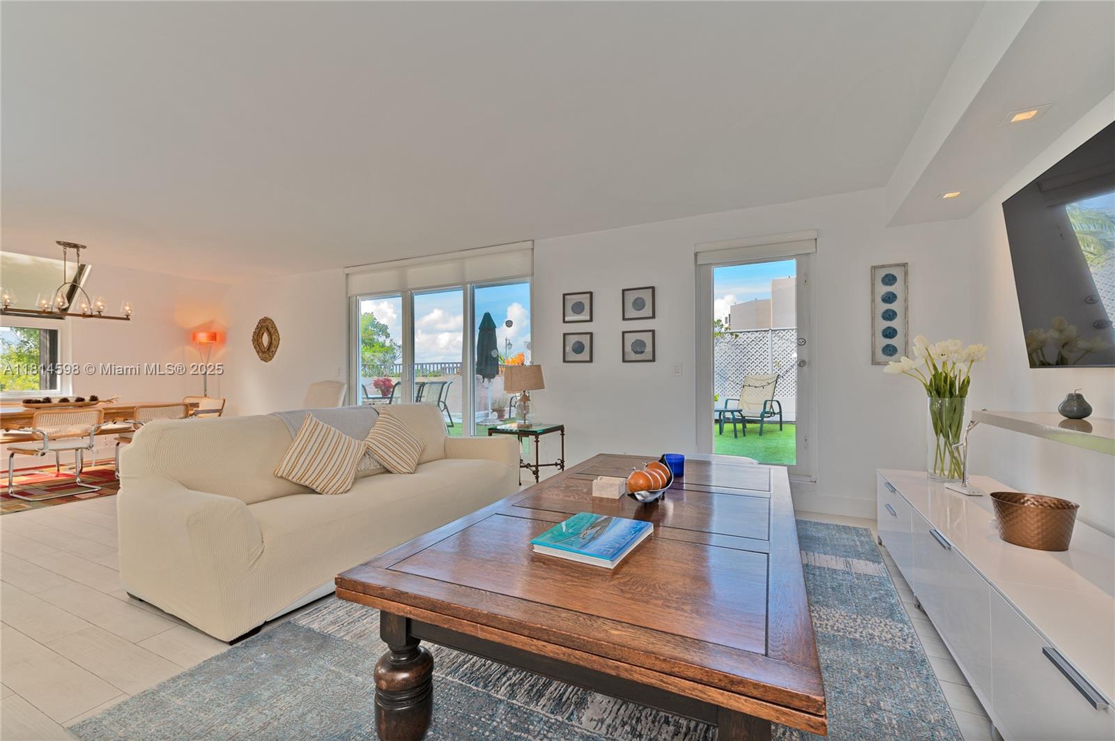 A bright living room features a beige sofa, wooden coffee table, and sliding glass doors — 101 Crandon Blvd # 480, Key Biscayne FL 33149, KEY BISCAYNE, FL