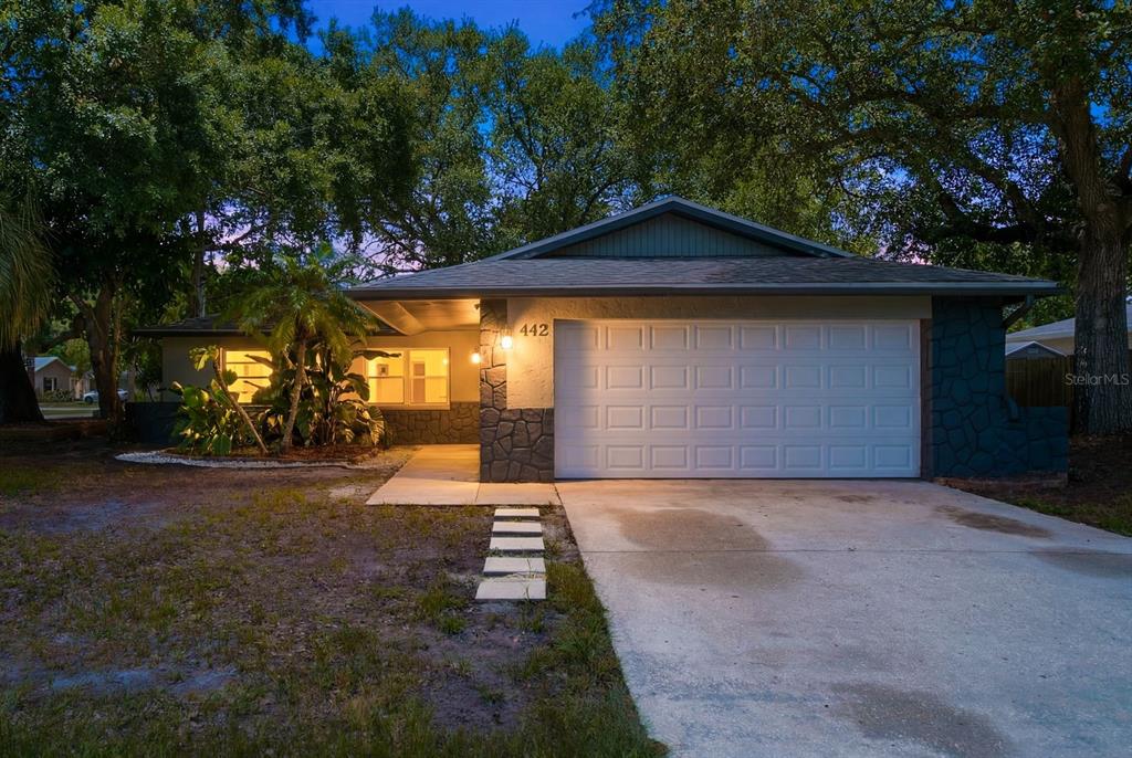 A single-story house with a white garage door, stone accents, and a concrete driveway — 442 EVERGREEN DRIVE, OLDSMAR, FL