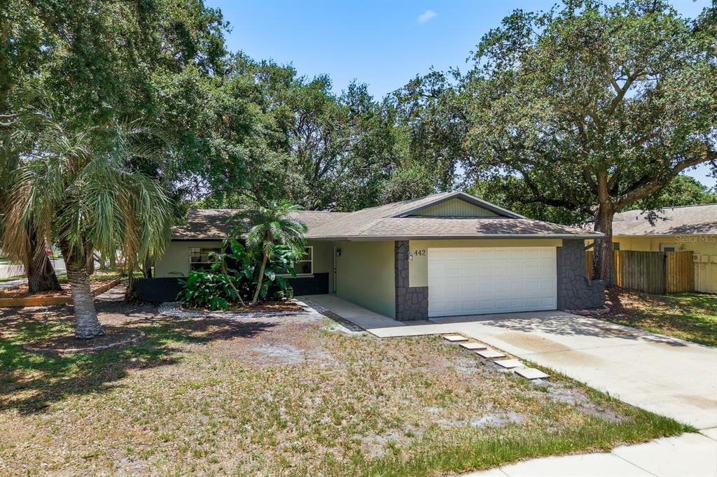 A single-story house with a beige exterior, a two-car garage, and mature trees in front — 442 EVERGREEN DRIVE, OLDSMAR, FL