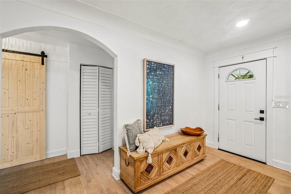 An entryway features a wooden storage bench, a barn door, and white walls with arched transitions — 4341 1ST AVENUE N, ST PETERSBURG, FL