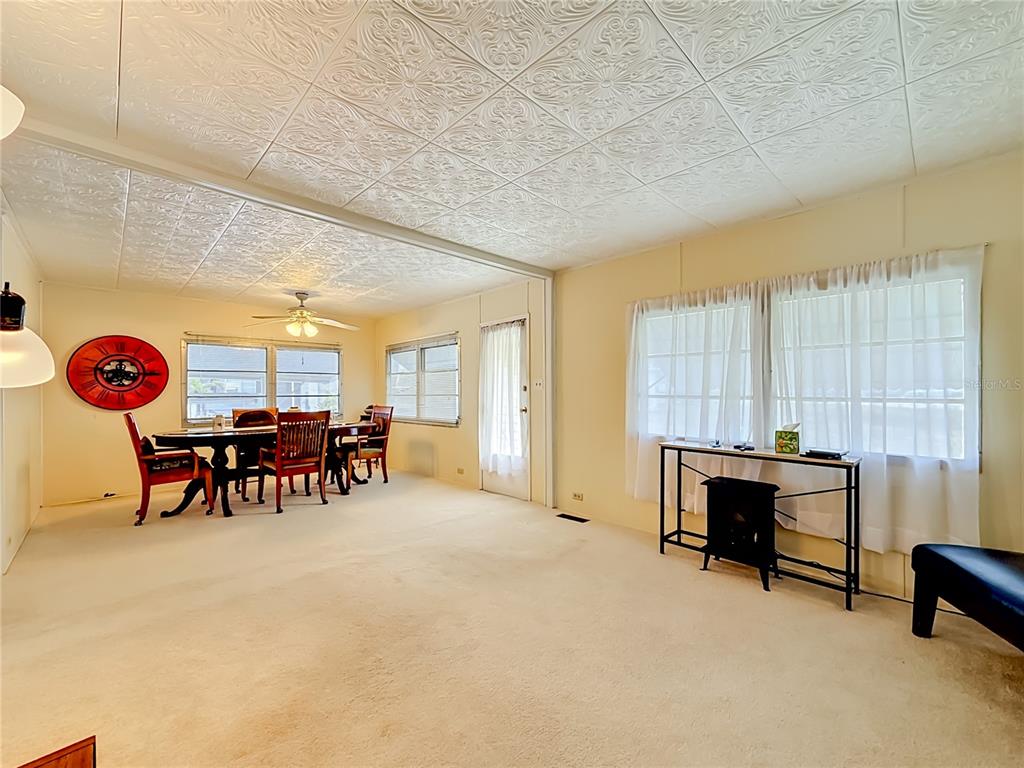 A dining area with a wooden table and chairs sits adjacent to a carpeted living space — 4676 66TH LANE N UNIT 20, ST PETERSBURG, FL
