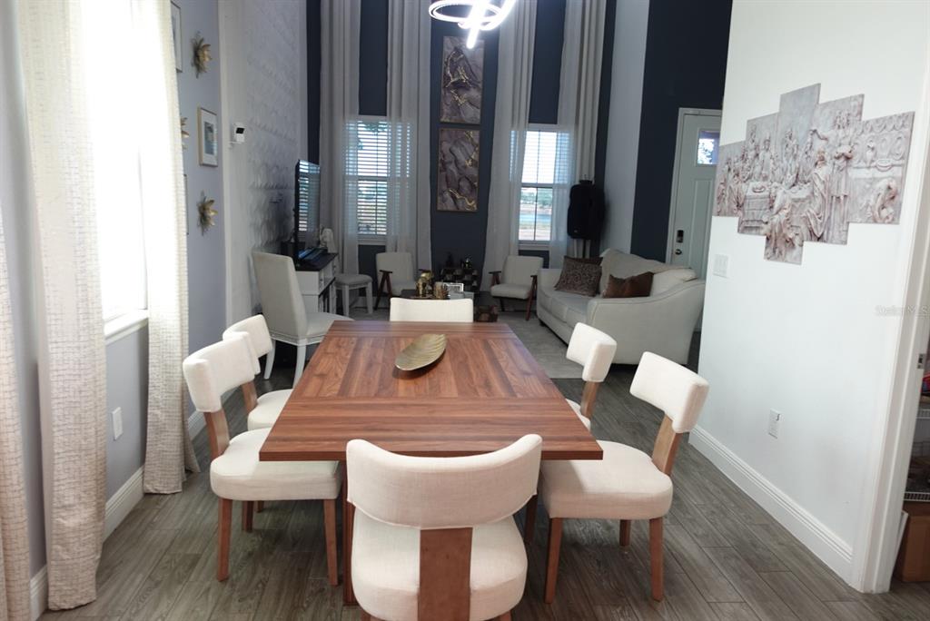 A dining area with a wooden table and cream chairs opens into a living room — 9803 AMBER CHESTNUT WAY, WINTER GARDEN, FL