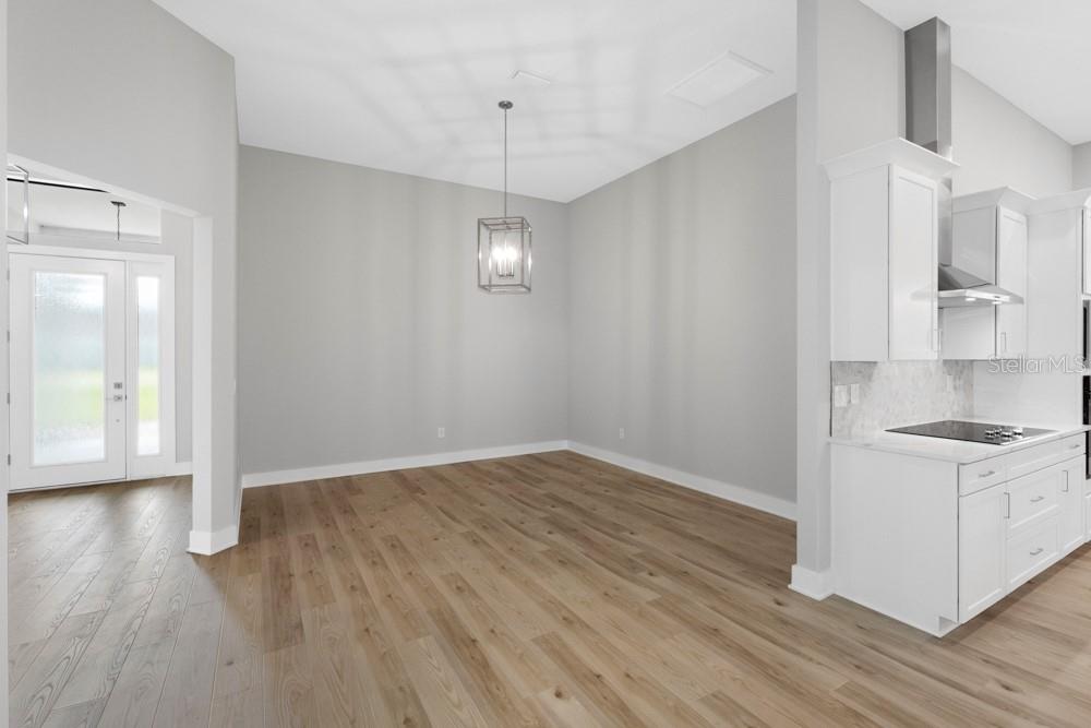 An open dining area features light wood flooring, gray walls, and a modern pendant light — 17444 NOKOTA AVENUE, HUDSON, FL