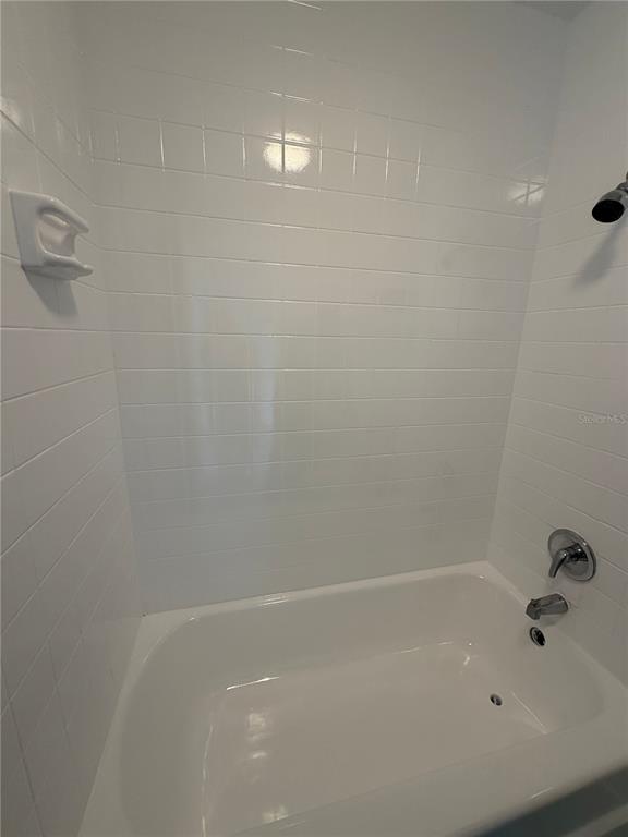 A white tiled bathtub and shower surround with chrome fixtures in a bathroom — 515 BON AIR STREET UNIT 160, LAKELAND, FL