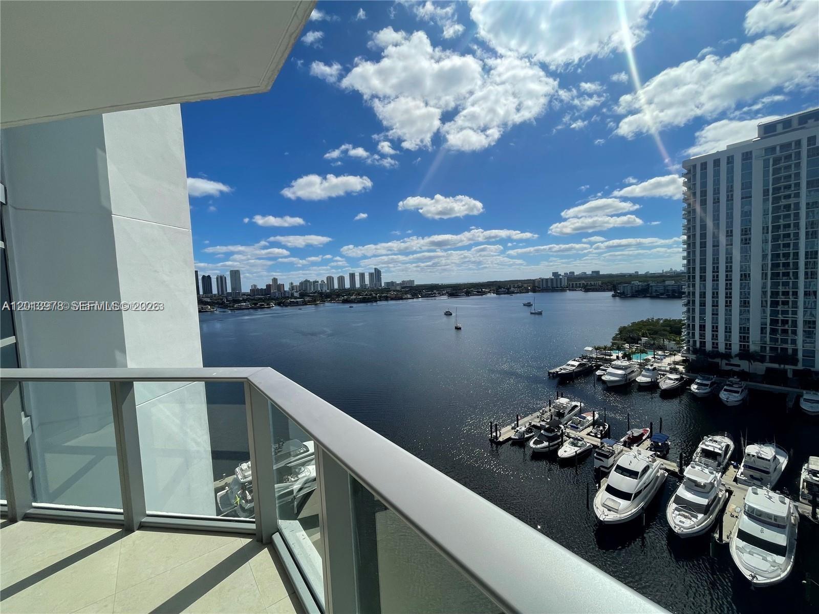 A balcony overlooks a marina with several yachts and a distant city skyline — NORTH MIAMI BEACH, FL
