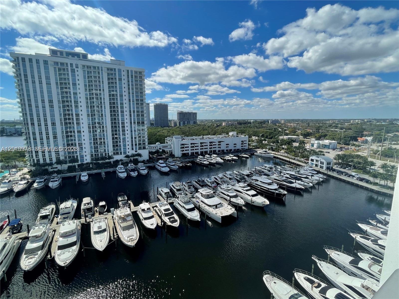 An elevated view shows a marina filled with numerous yachts docked beside a tall building — NORTH MIAMI BEACH, FL