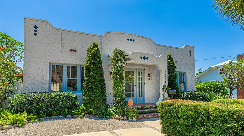 A white stucco house with a flat roof, blue window frames, and manicured landscaping — 2327 7TH AVENUE W, BRADENTON, FL