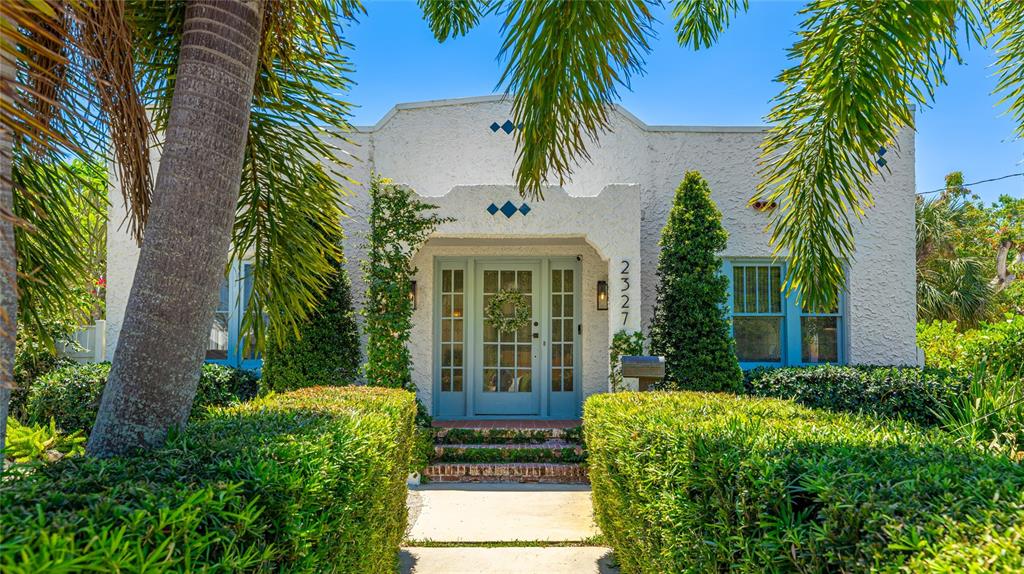 A white stucco house with a blue front door and trimmed hedges under palm trees — 2327 7TH AVENUE W, BRADENTON, FL