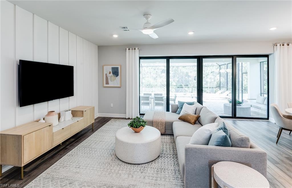 A modern living room features a white paneled accent wall, gray sectional sofa, and sliding doors — 294 Silent Lake, Lehigh Acres FL 33936, LEHIGH ACRES, FL