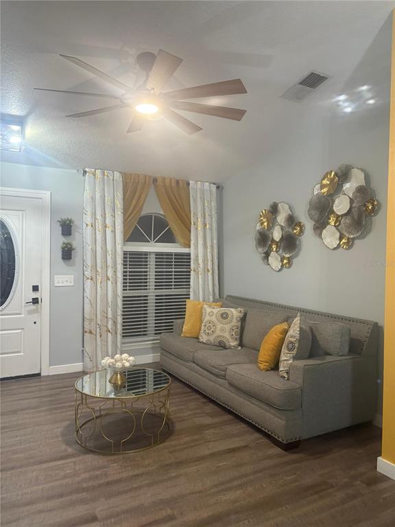 A living room features a grey sofa, a round mirrored coffee table, and gold accents — 124 GUADALAJARA DRIVE, KISSIMMEE, FL
