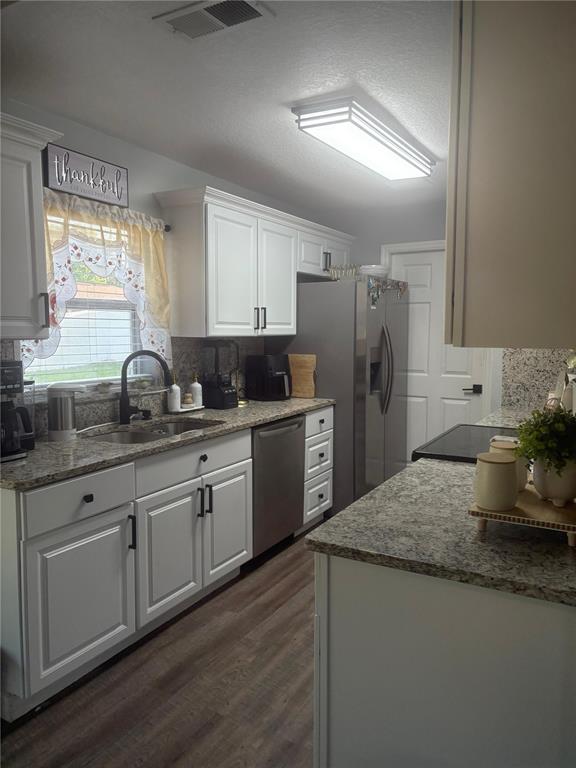 A kitchen features white cabinets, granite countertops, stainless steel appliances, and wood-look flooring — 124 GUADALAJARA DRIVE, KISSIMMEE, FL