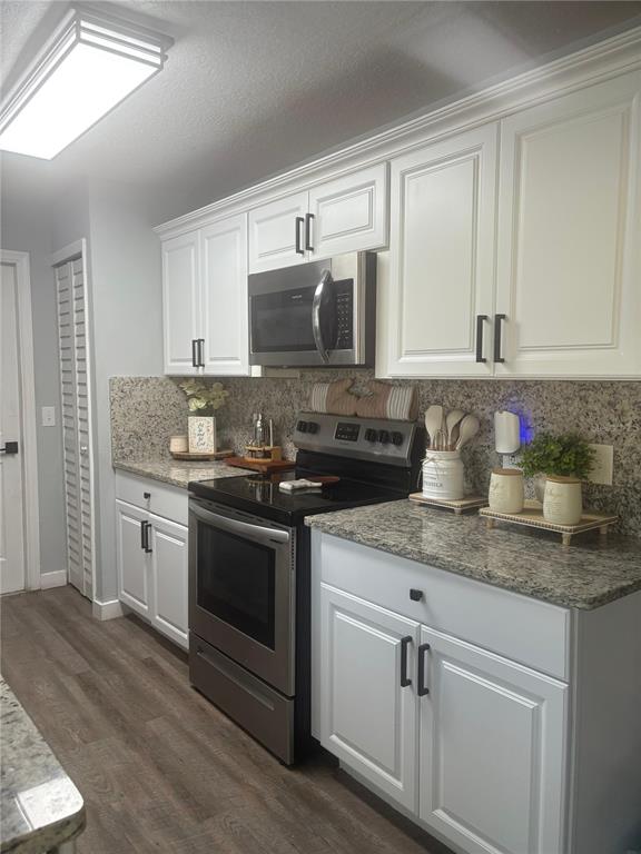 A kitchen features white cabinets, granite countertops, stainless steel appliances, and wood-look flooring — 124 GUADALAJARA DRIVE, KISSIMMEE, FL