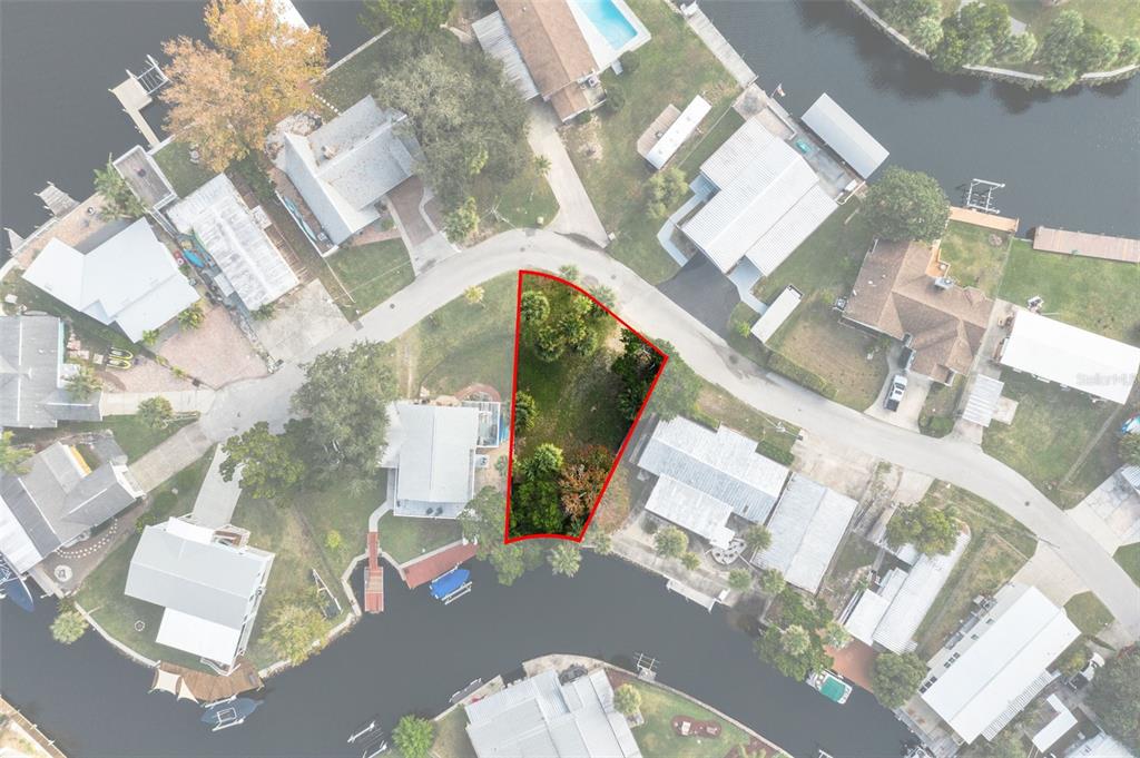 This aerial view shows a vacant, trapezoidal waterfront lot outlined in red — 10199 W BLUE SPRINGS COURT, HOMOSASSA, FL