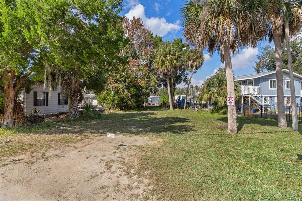 A vacant, grassy lot sits between two houses under a bright, partly cloudy sky — 10199 W BLUE SPRINGS COURT, HOMOSASSA, FL