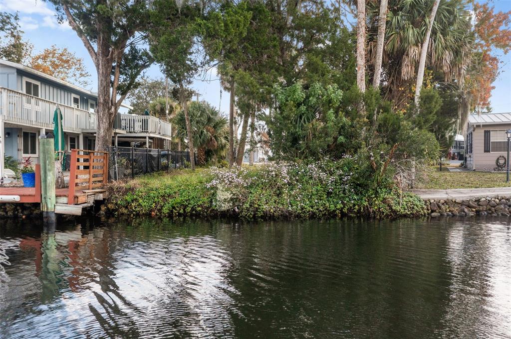 A waterfront view of a house with a wooden deck and dock beside a canal — 10199 W BLUE SPRINGS COURT, HOMOSASSA, FL