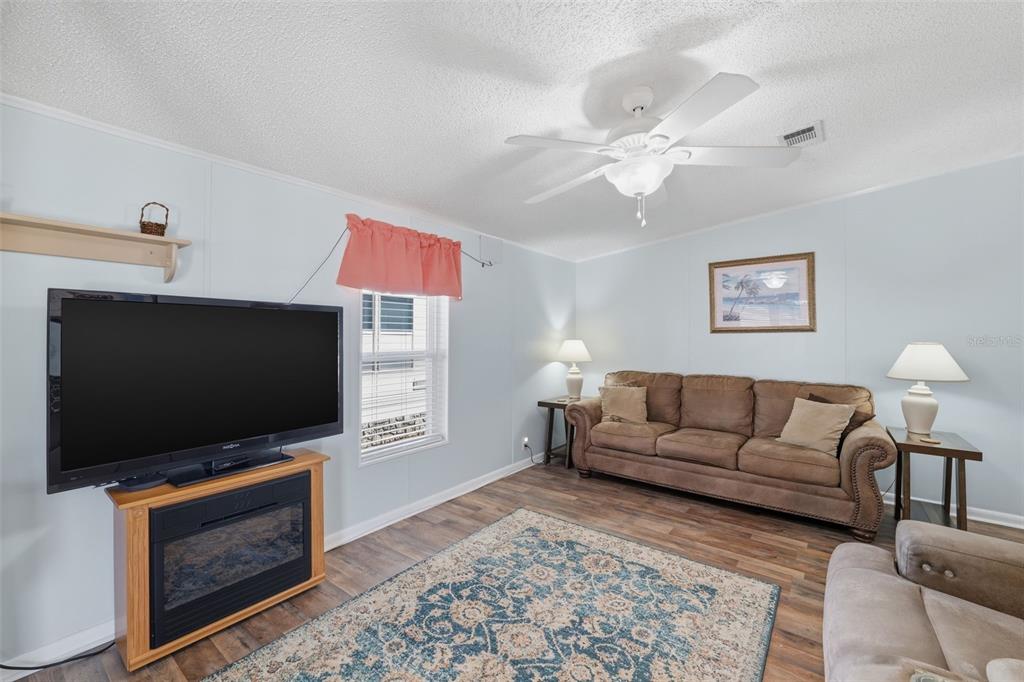 A living room features a brown sofa, a television on a fireplace stand, and flooring — 326 NESBITT PARK AVENUE, DAVENPORT, FL