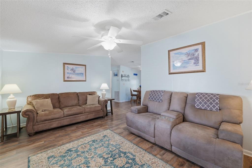 A living room features two brown sofas, a patterned area rug, and a ceiling fan — 326 NESBITT PARK AVENUE, DAVENPORT, FL