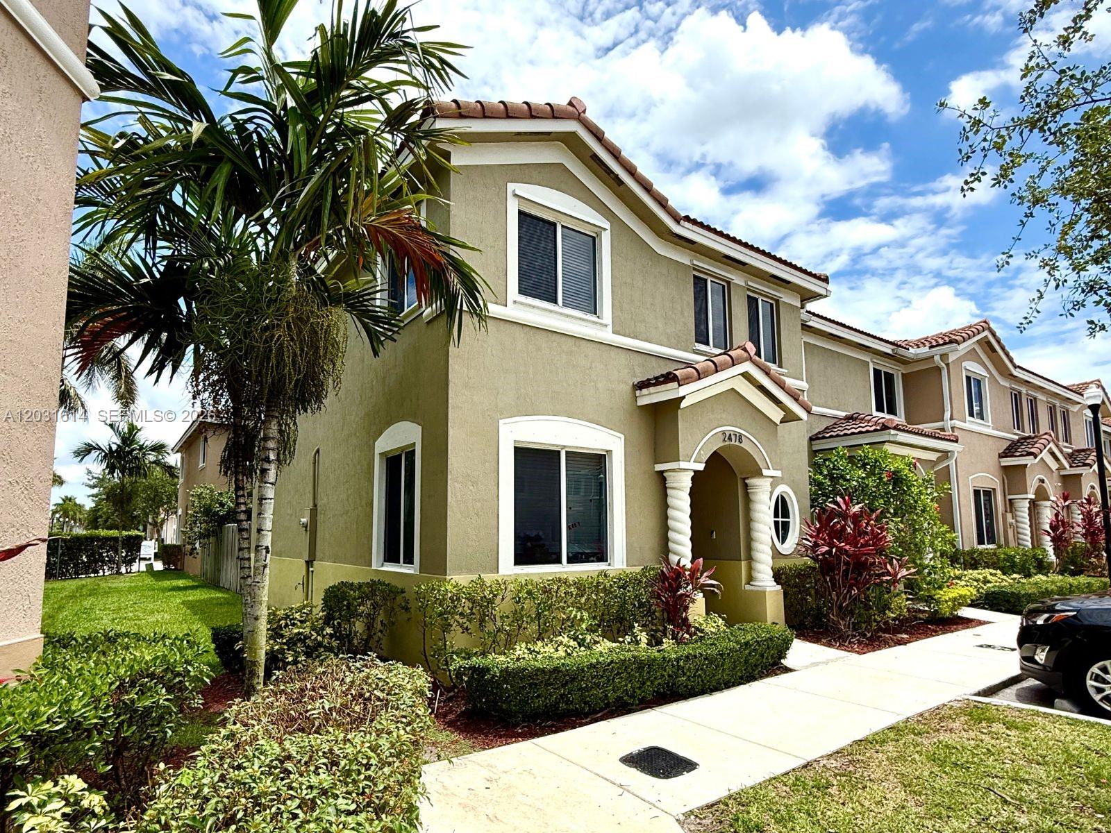 A covered patio features gray tile flooring, a ceiling fan, and a wooden privacy fence — HOMESTEAD, FL