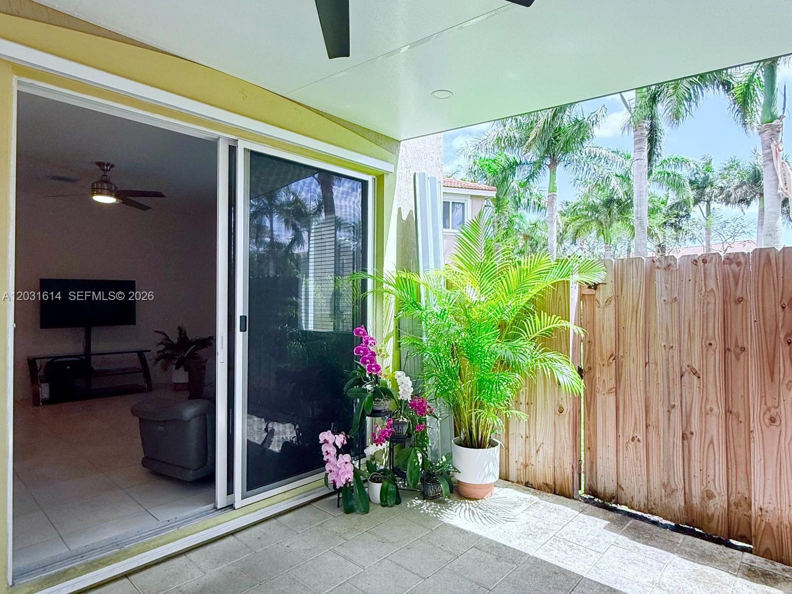 An open-concept kitchen features dark cabinetry, a white island with bar seating, and tile flooring — HOMESTEAD, FL