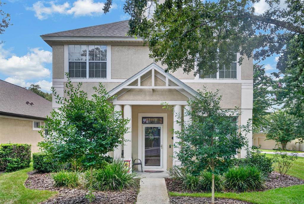 A two-story house with a beige stucco exterior, a front porch, and a walkway — 239 W TARRINGTON DRIVE, DELAND, FL