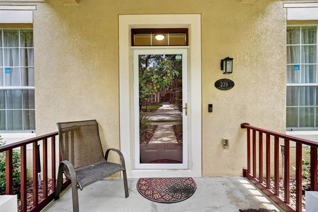A front porch features a glass storm door, a single chair, and a house number plaque — 239 W TARRINGTON DRIVE, DELAND, FL