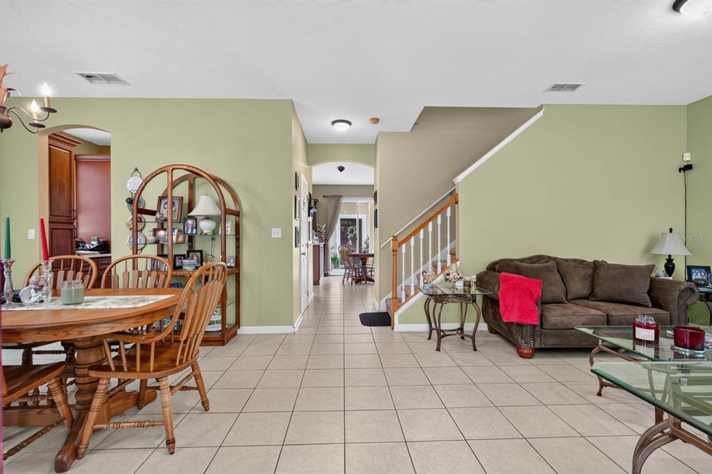 A dining area and living room with tile floors, a staircase, and light green walls — 239 W TARRINGTON DRIVE, DELAND, FL