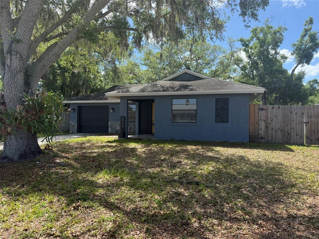 A single-story house with blue stucco siding, a dark garage door, and a large oak tree — 2332 SEWARD DRIVE, SARASOTA, FL