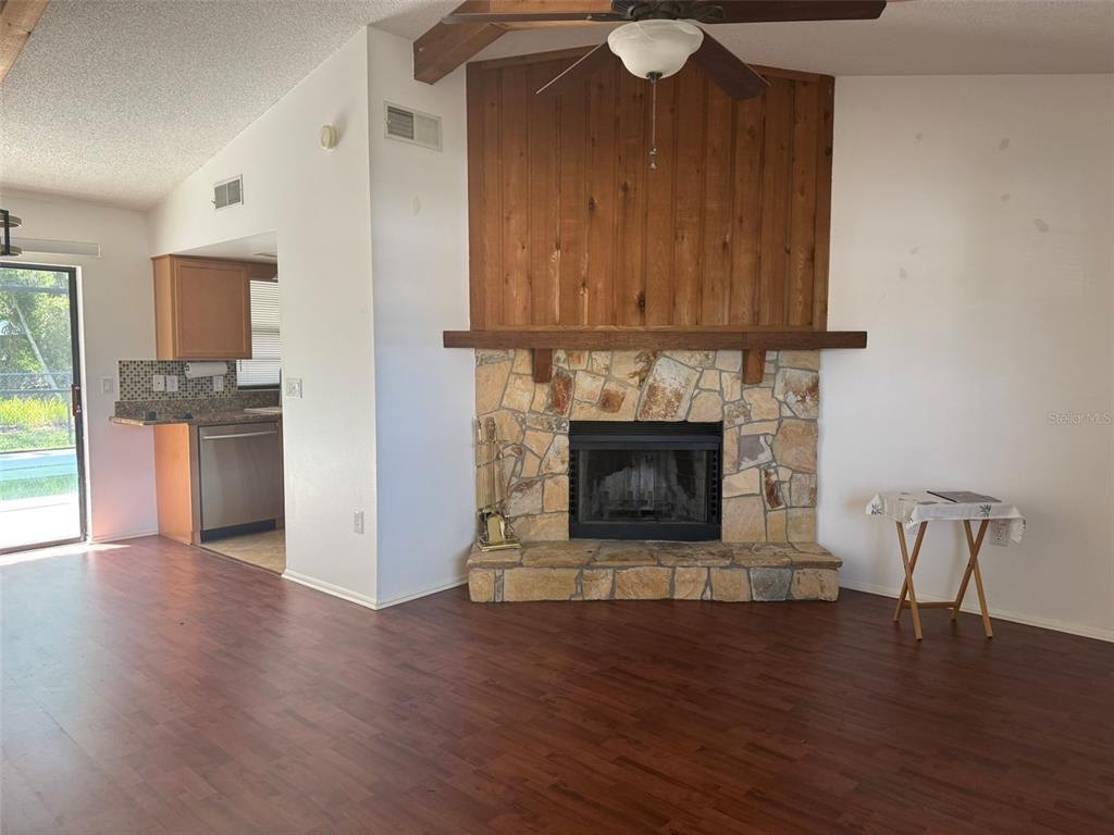 A living room features a stone fireplace with a wood-paneled chimney breast and wood flooring — 2332 SEWARD DRIVE, SARASOTA, FL