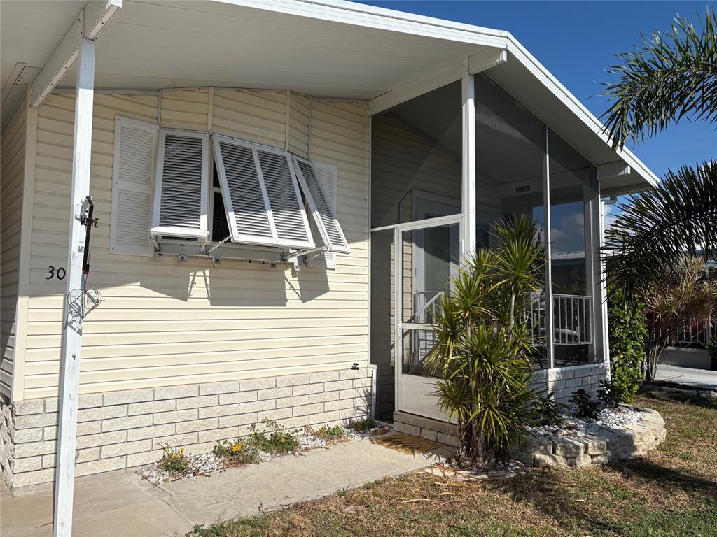 A single-story mobile home with a carport, light siding, and a palm tree in front — 3002 12TH STREET W, PALMETTO, FL