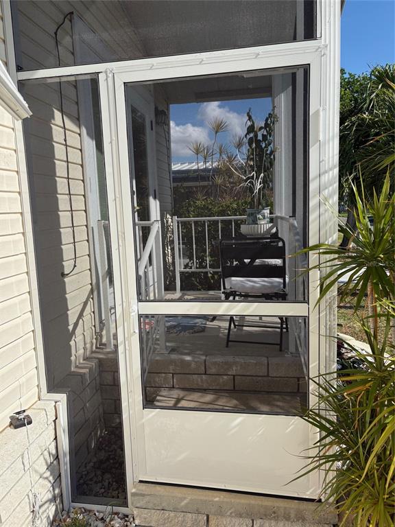 A covered patio features a concrete floor, lounge chairs, a dining set, and floral wall art — 3002 12TH STREET W, PALMETTO, FL