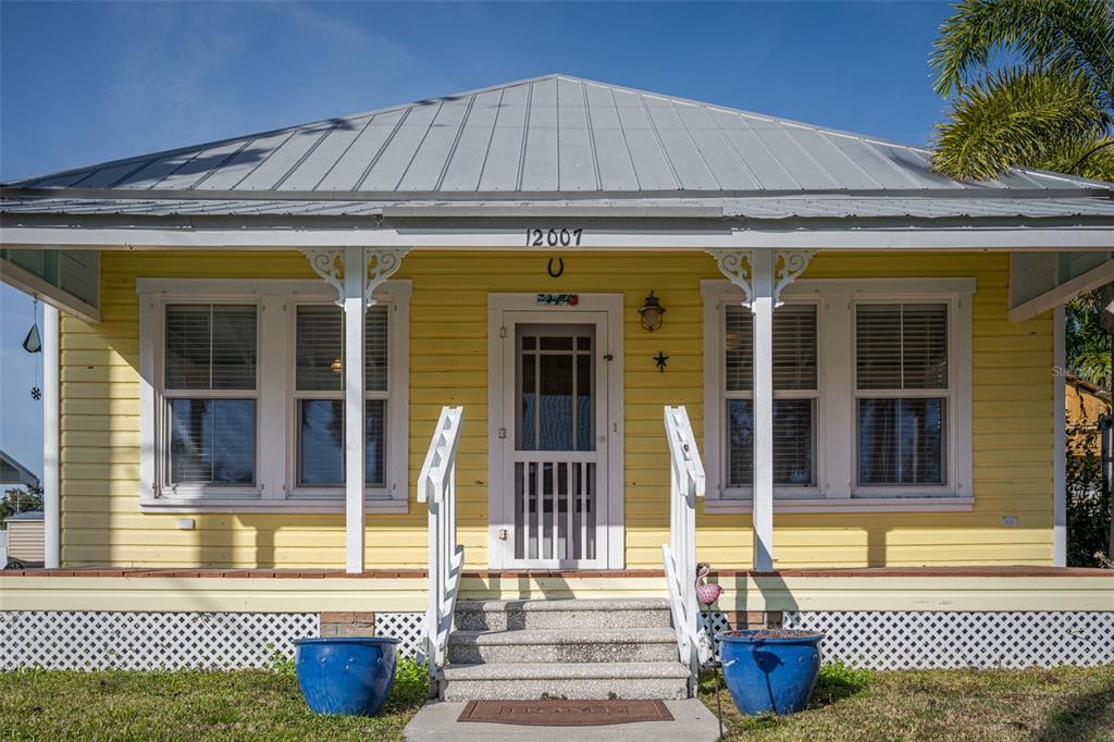 A yellow house with a metal roof and a front porch with white railings — 12007 45TH AVENUE W, CORTEZ, FL