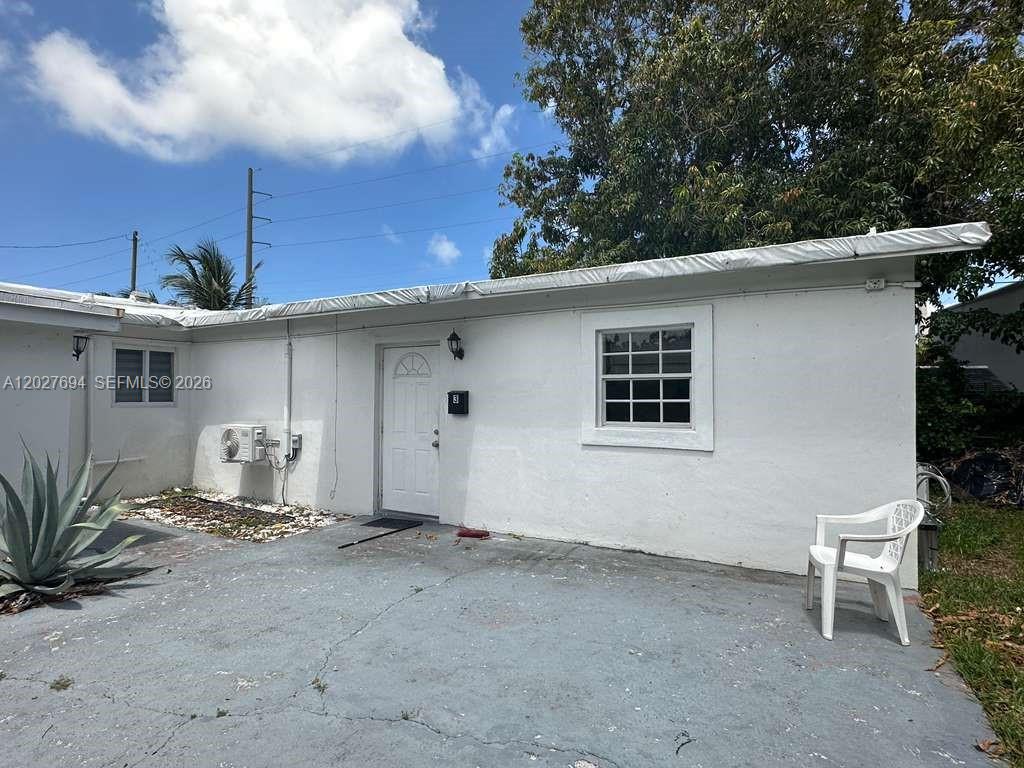 A white, single-story building exterior features a white door, a grid-pane window, and a patio — 685 SW 7th Terr, Dania Beach FL 33004, DANIA BEACH, FL