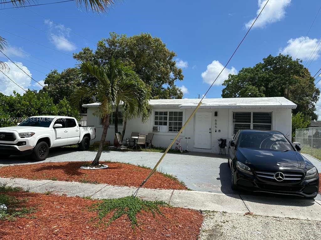 A white single-story house features a concrete driveway with two parked cars and landscaping — 685 SW 7th Terr, Dania Beach FL 33004, DANIA BEACH, FL