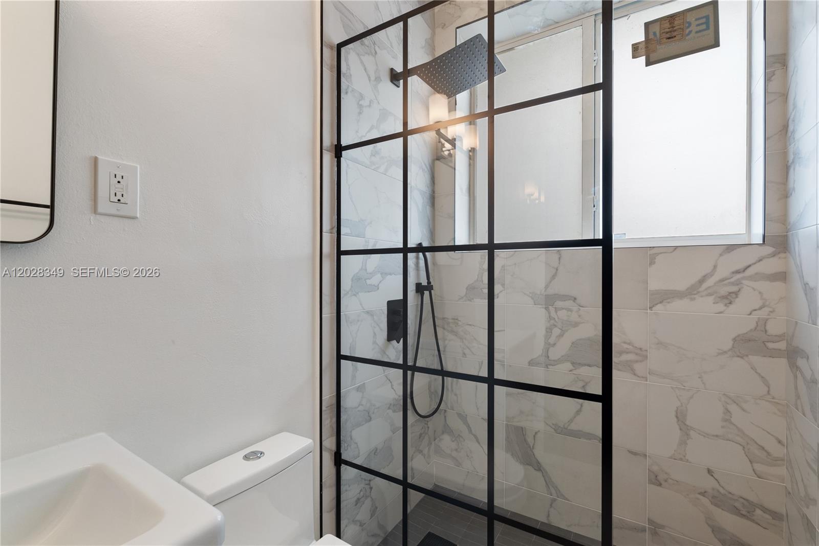 A bathroom features a walk-in shower with a black grid frame and marble-look tile — 2204 Mckinley St # 2, Hollywood FL 33020, HOLLYWOOD, FL