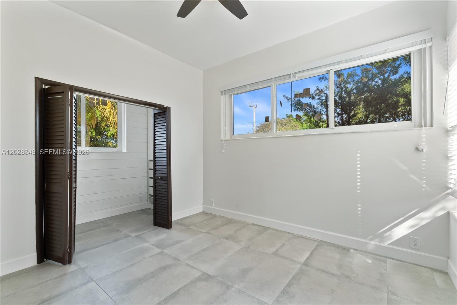 A bedroom features large gray floor tiles, white walls, and a closet with louvered doors — 2204 Mckinley St # 2, Hollywood FL 33020, HOLLYWOOD, FL
