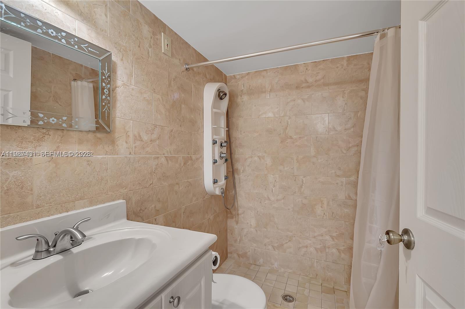 A bathroom features a white vanity, a tiled walk-in shower with a panel system, and a mirror — 6580 W 27th Ct # 12, Hialeah FL 33016, HIALEAH, FL