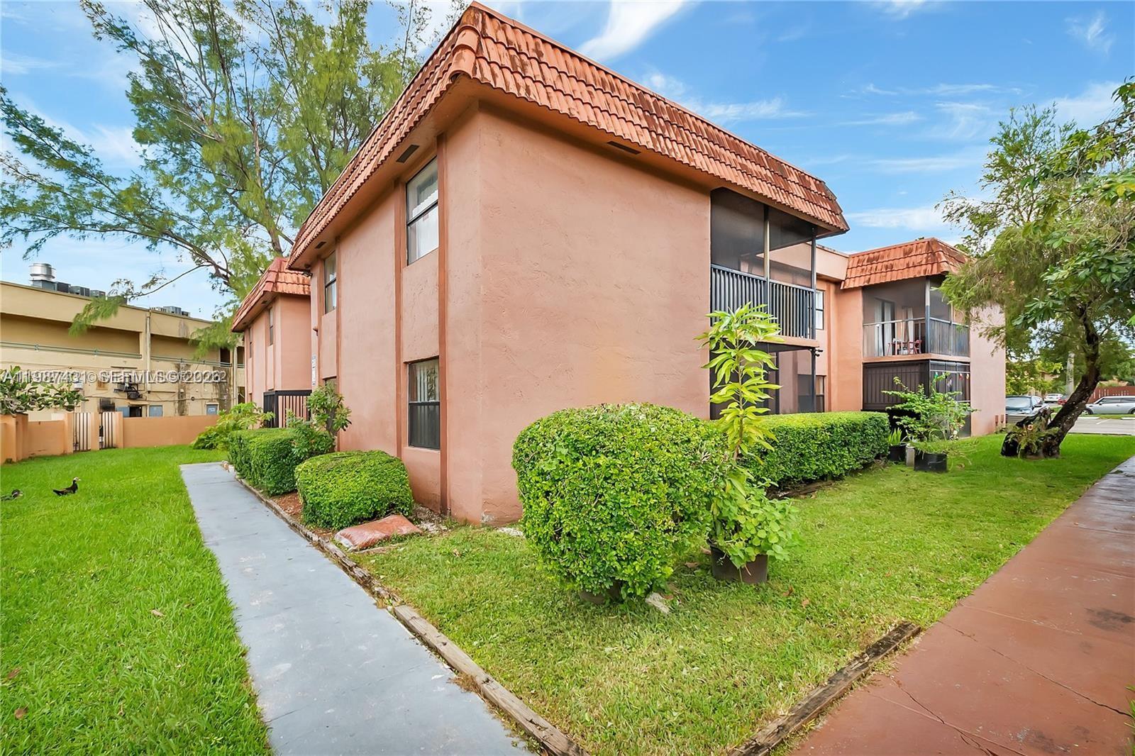 The exterior of a two-story stucco apartment building features a brown tile roof and balconies — 6580 W 27th Ct # 12, Hialeah FL 33016, HIALEAH, FL