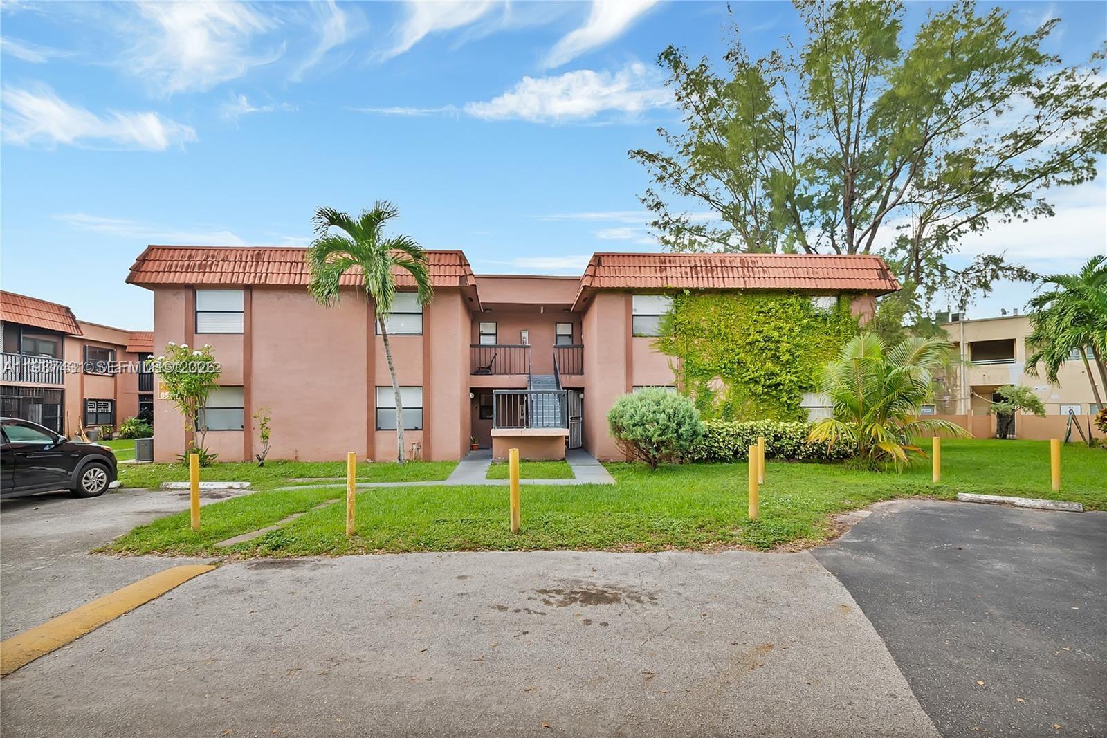 A two-story pink apartment building features a brown tile roof and a central staircase — 6580 W 27th Ct # 12, Hialeah FL 33016, HIALEAH, FL