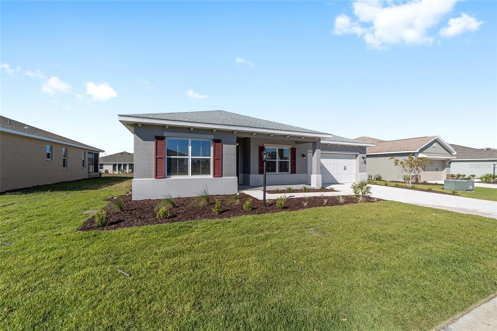 A single-story house with gray stucco siding, red shutters, and a two-car garage — 10019 SW 106TH CIRCLE, OCALA, FL
