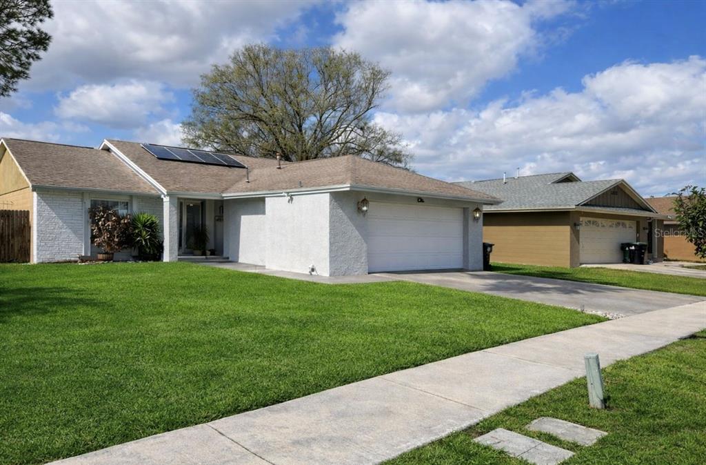 A single-story house with a white stucco exterior, a two-car garage, and solar panels — 2217 PAPRIKA DRIVE, ORLANDO, FL