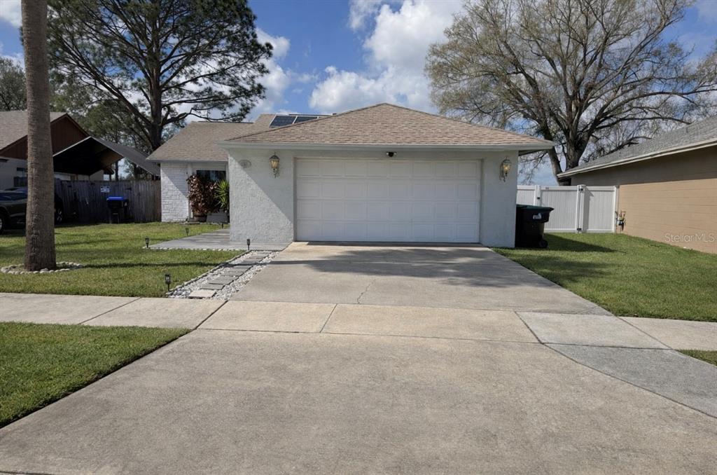 A single-story house with a white stucco exterior, a two-car garage, and a concrete driveway — 2217 PAPRIKA DRIVE, ORLANDO, FL