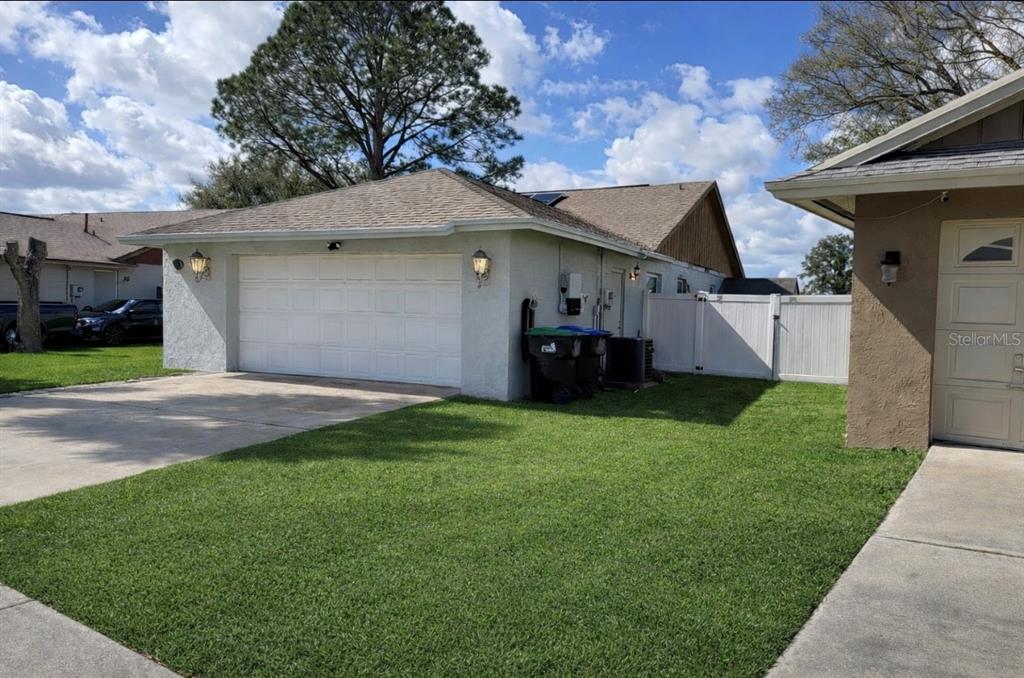A white garage with a concrete driveway and a white vinyl fence in the yard — 2217 PAPRIKA DRIVE, ORLANDO, FL