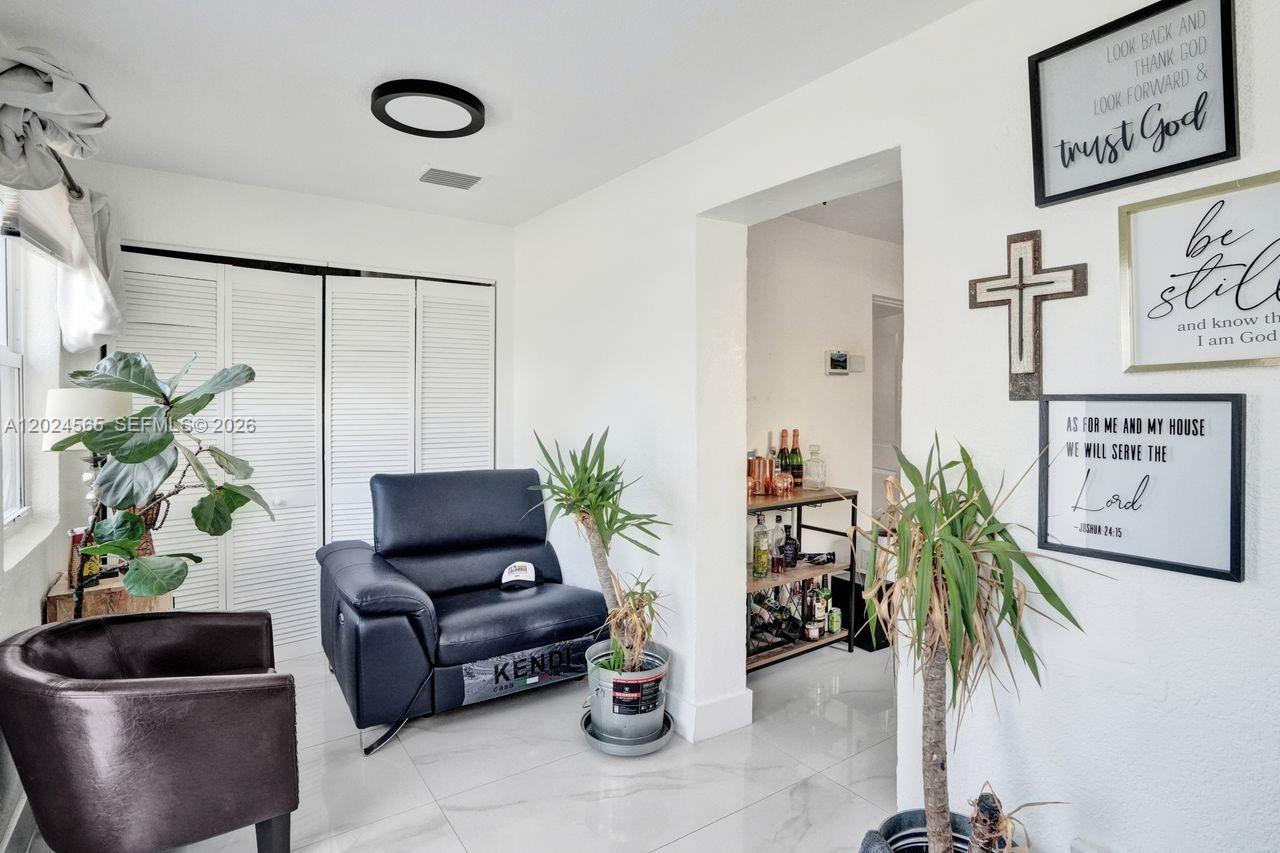 A living area features white walls, tile flooring, a dark leather chair, and wall-mounted decor — 2220 Hope St, Hollywood FL 33020, HOLLYWOOD, FL