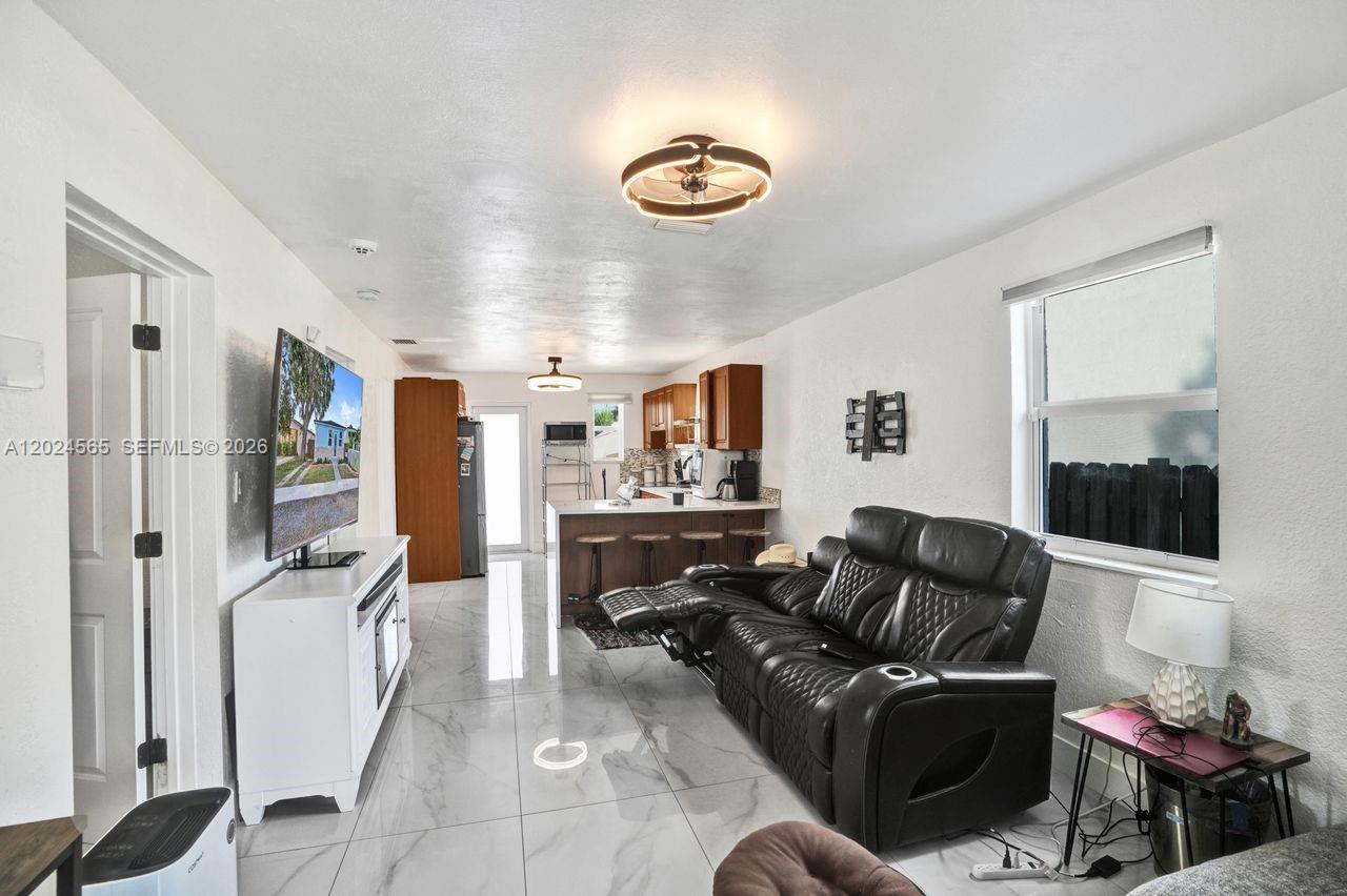 A living room with white tile floors, a black leather recliner, and an open kitchen — 2220 Hope St, Hollywood FL 33020, HOLLYWOOD, FL