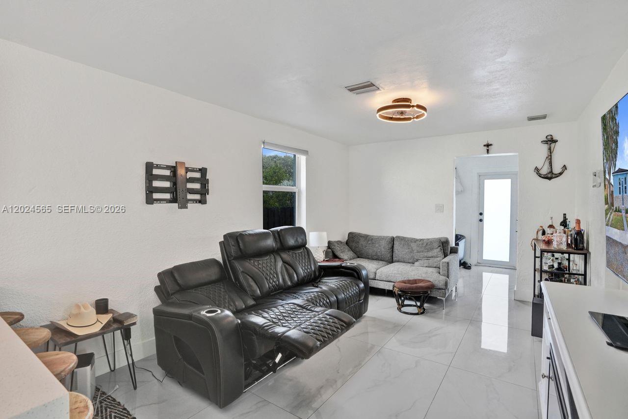 A living room features a black reclining sofa, a grey sofa, and white tile flooring — 2220 Hope St, Hollywood FL 33020, HOLLYWOOD, FL