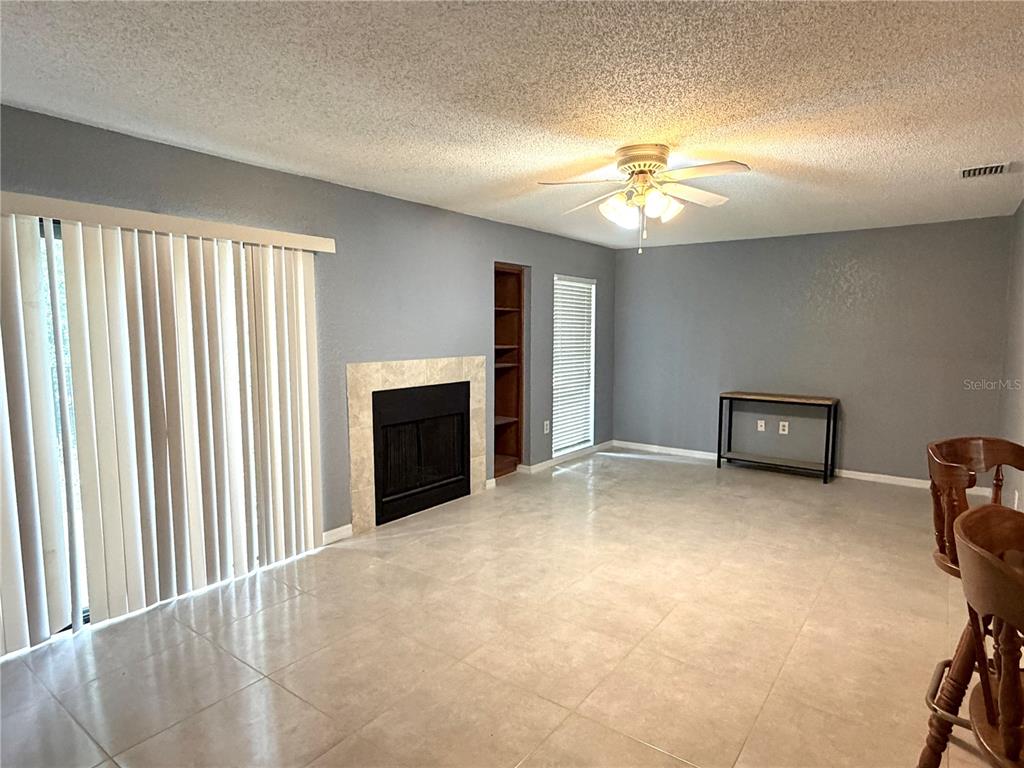A living room features gray walls, tile flooring, a fireplace, and a ceiling fan — 564 BRECKENRIDGE VILLAGE UNIT 106, ALTAMONTE SPRINGS, FL
