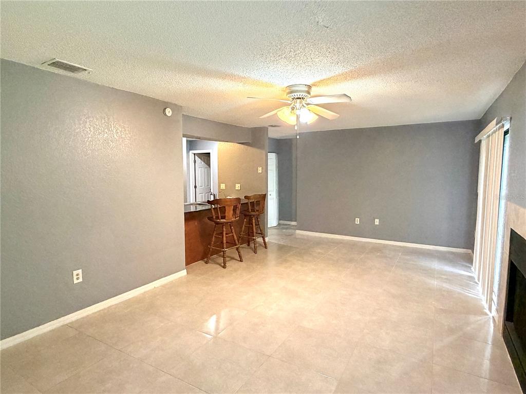 A living room with gray walls, tile flooring, a ceiling fan, and a breakfast bar — 564 BRECKENRIDGE VILLAGE UNIT 106, ALTAMONTE SPRINGS, FL